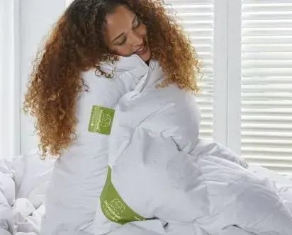 Vrouw knuffelt een wit dekbed.