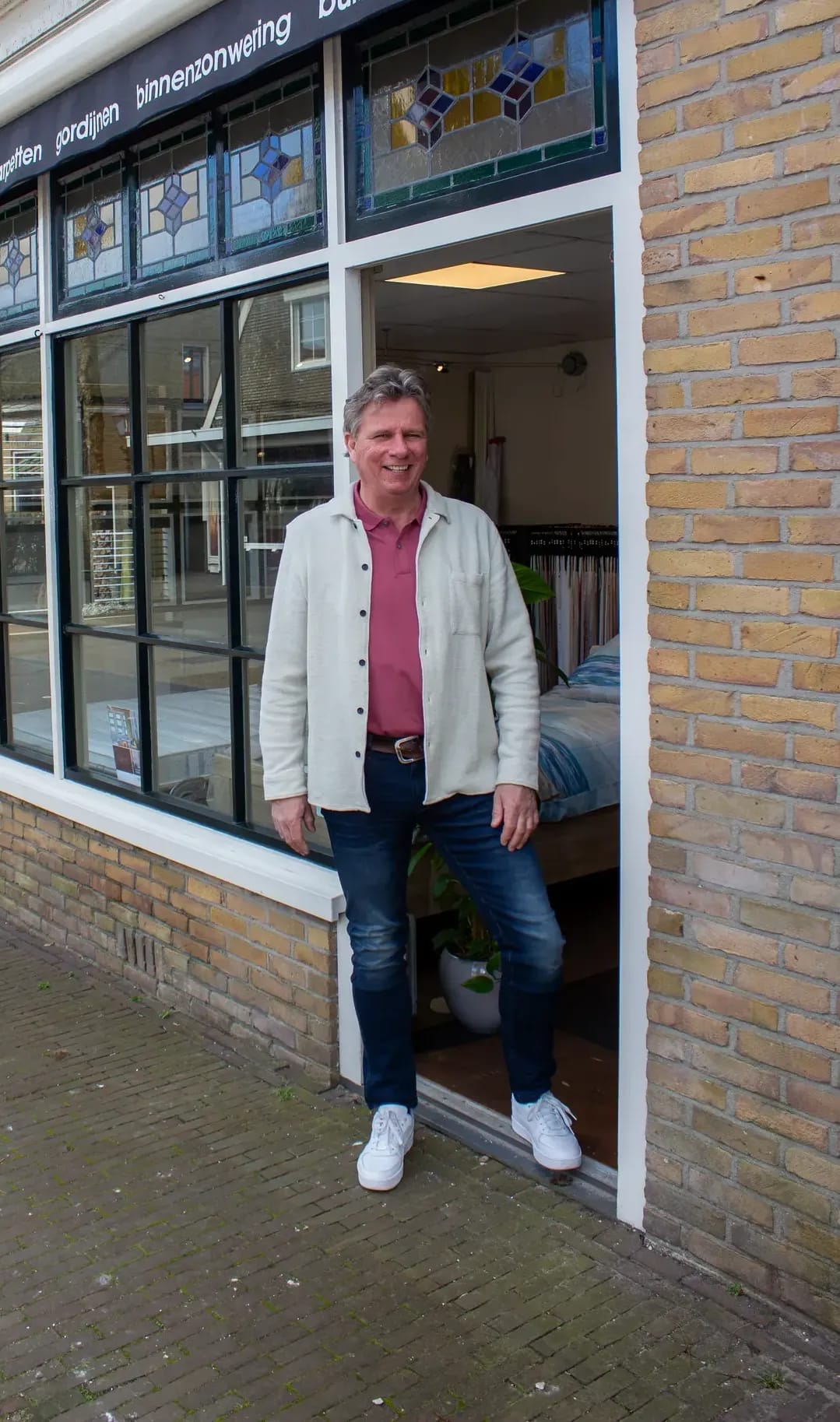 Gevel van de showroom op Terschelling met glas-in-loodramen; een medewerker staat in de deur.