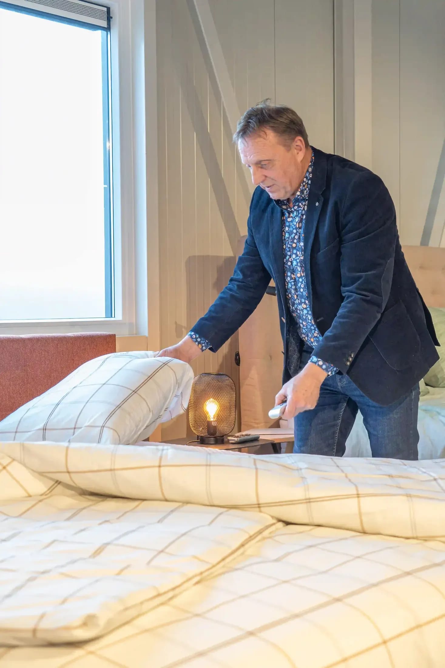Adviseur maakt een bed met geruit beddengoed op in de showroom.