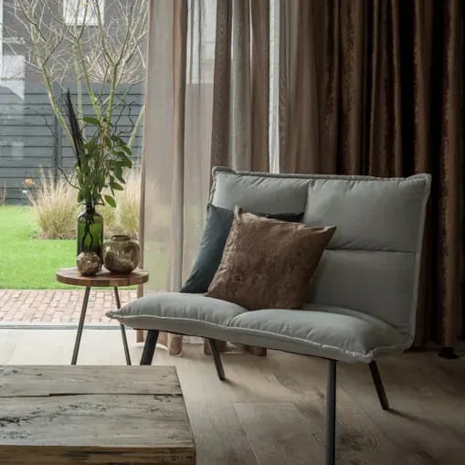 Inbetweens in brons en goud naast een lounge-bank met sierkussen.
