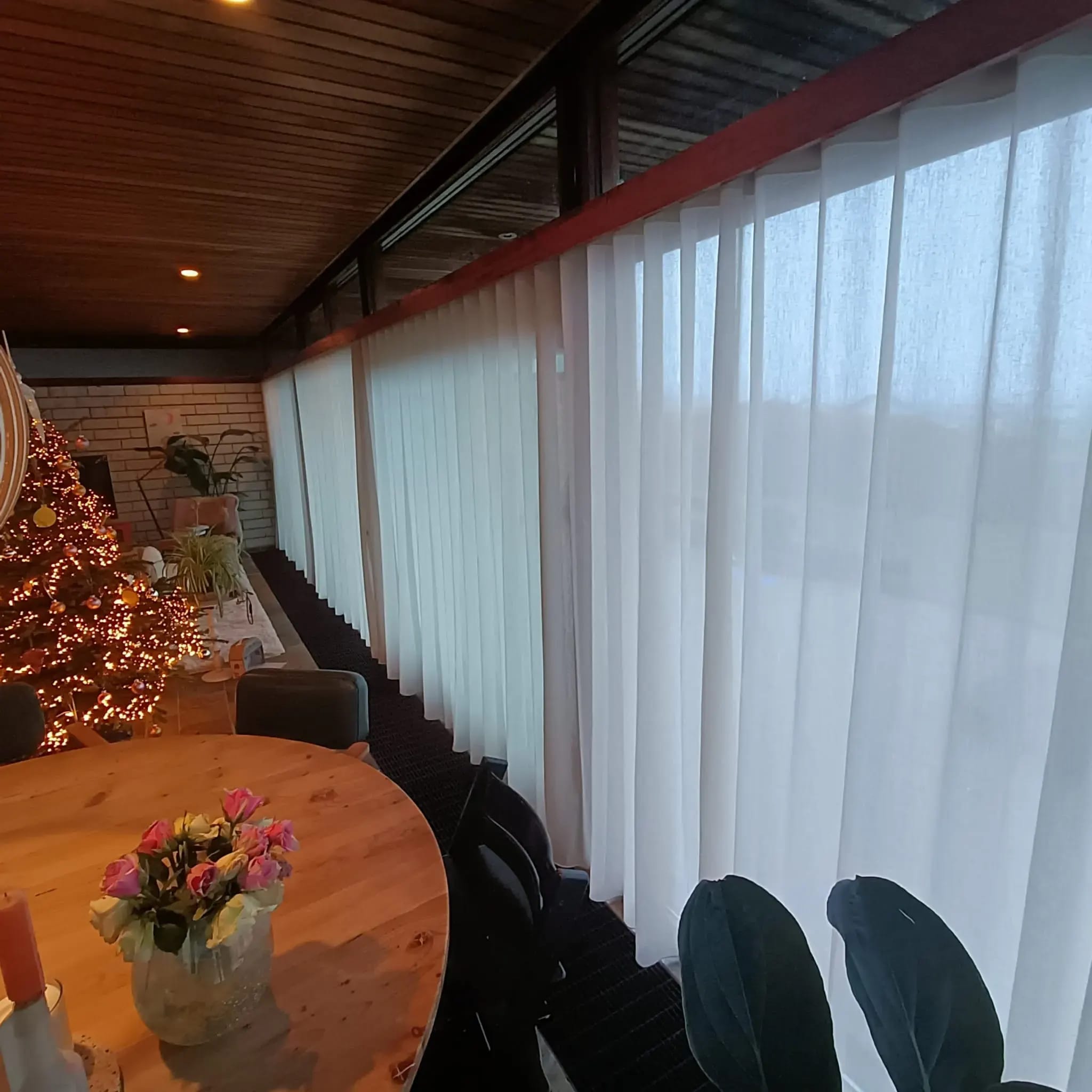 Lichte inbetweens over de hele lengte van een glazen pui, met een eettafel ervoor.