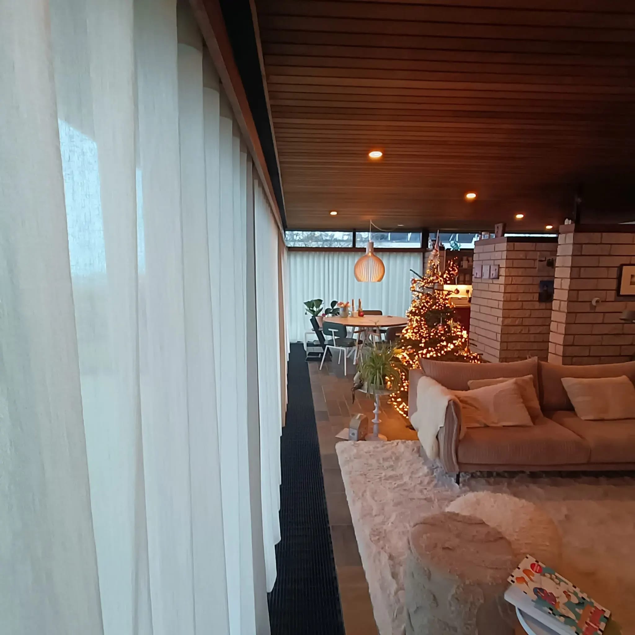 Inbetweens langs de ramen van een woonkamer, met zicht op de zithoek.
