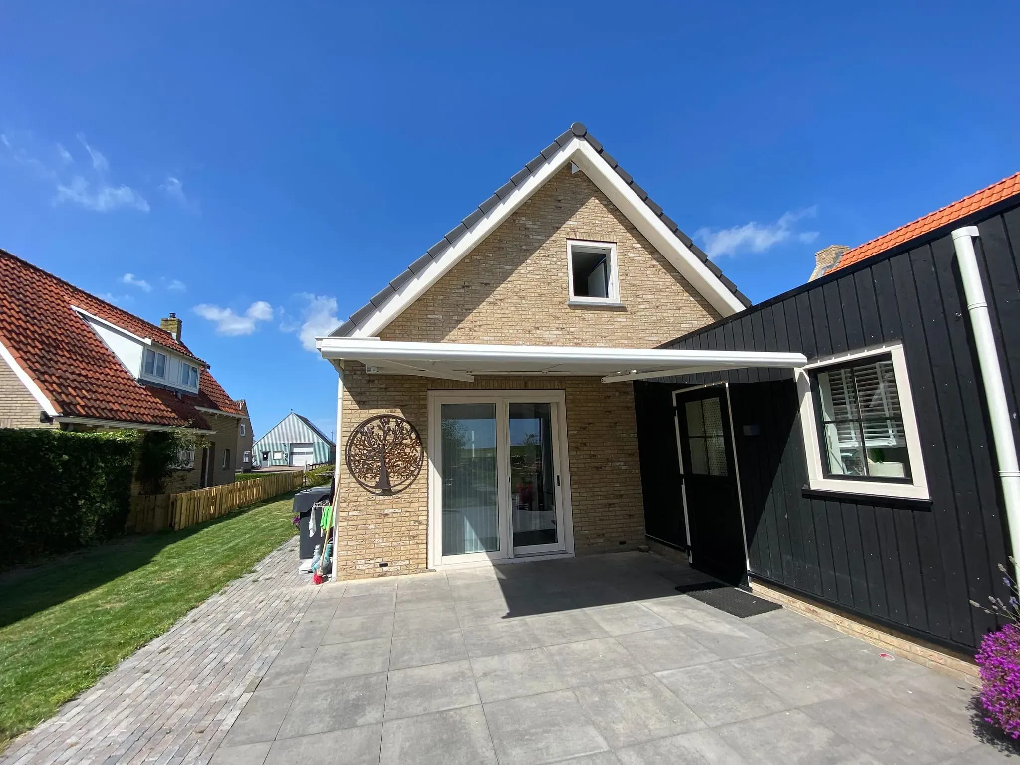 Woning op Terschelling met een ingeklapt knikarmscherm boven de tuindeuren.