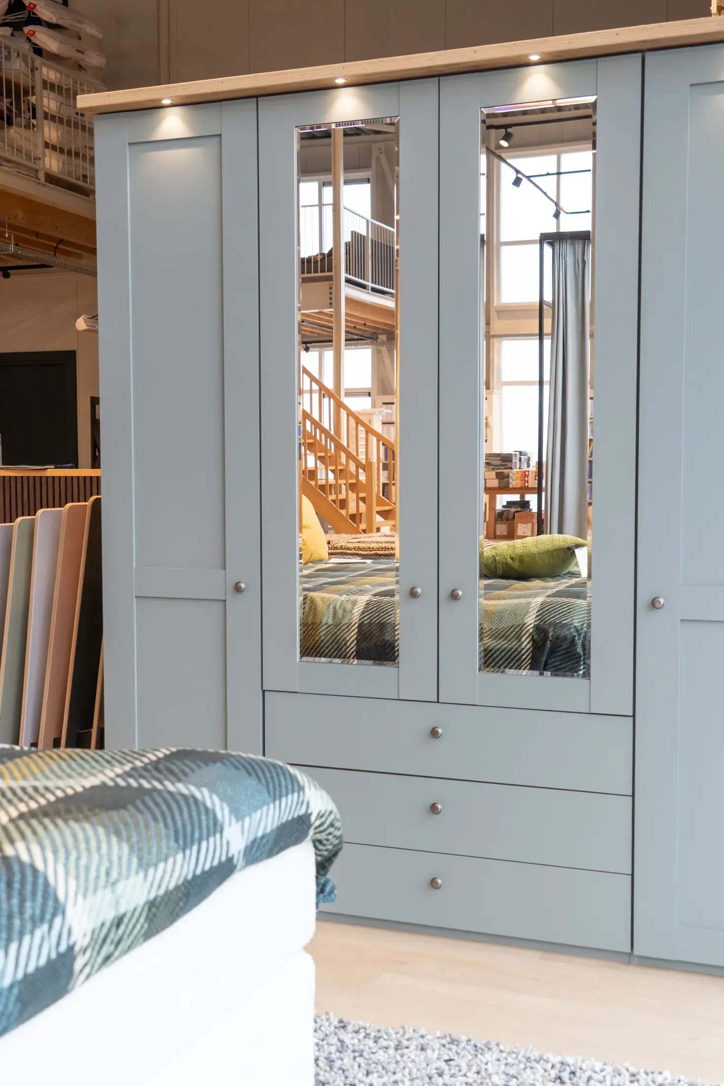 Lichtblauwe linnenkast met spiegeldeuren en lades in de showroom.