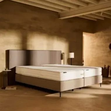 Dik matras op een boxspring in een warme slaapkamer.