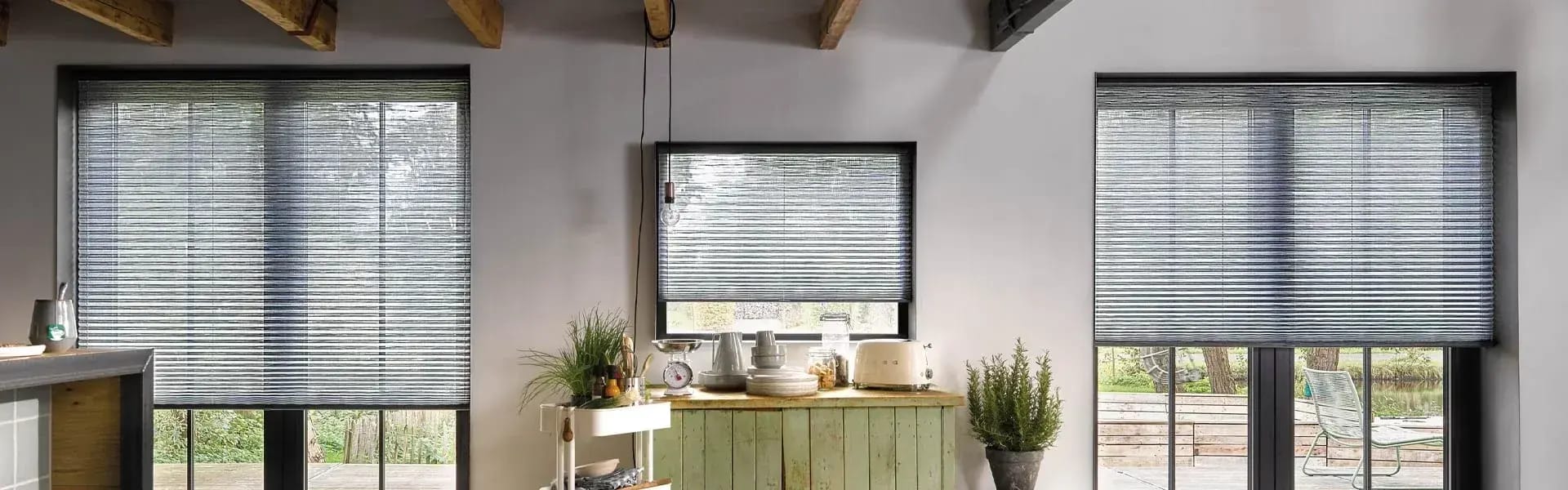 Plisségordijnen voor de ramen van een keuken met houten balken.