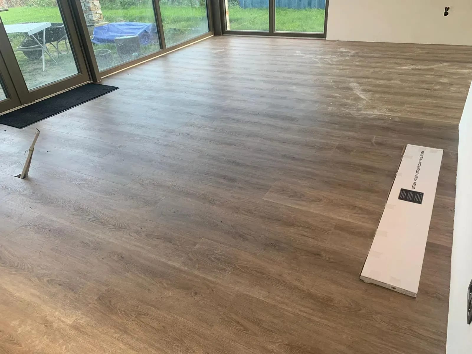 Donkere PVC-vloer in een woonkamer met glazen pui.