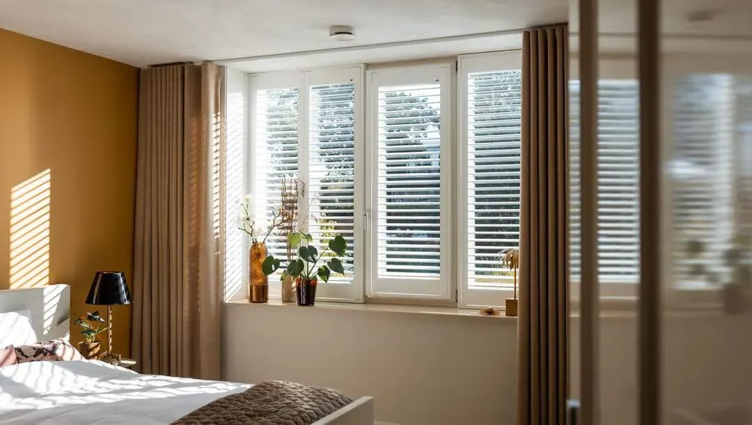 Witte shutters voor de ramen van een slaapkamer.