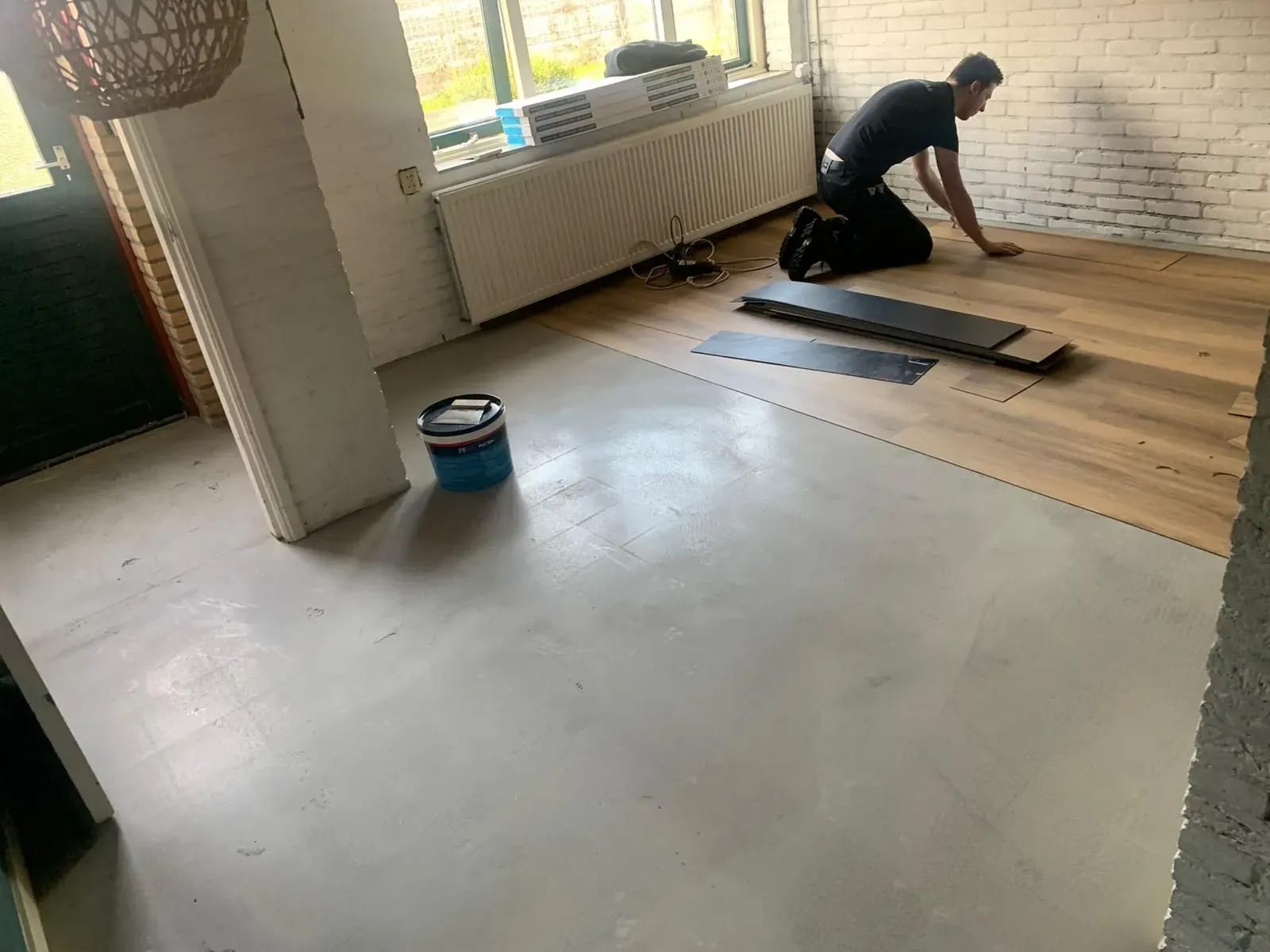 Vakman legt PVC-planken op een geëgaliseerde ondervloer.