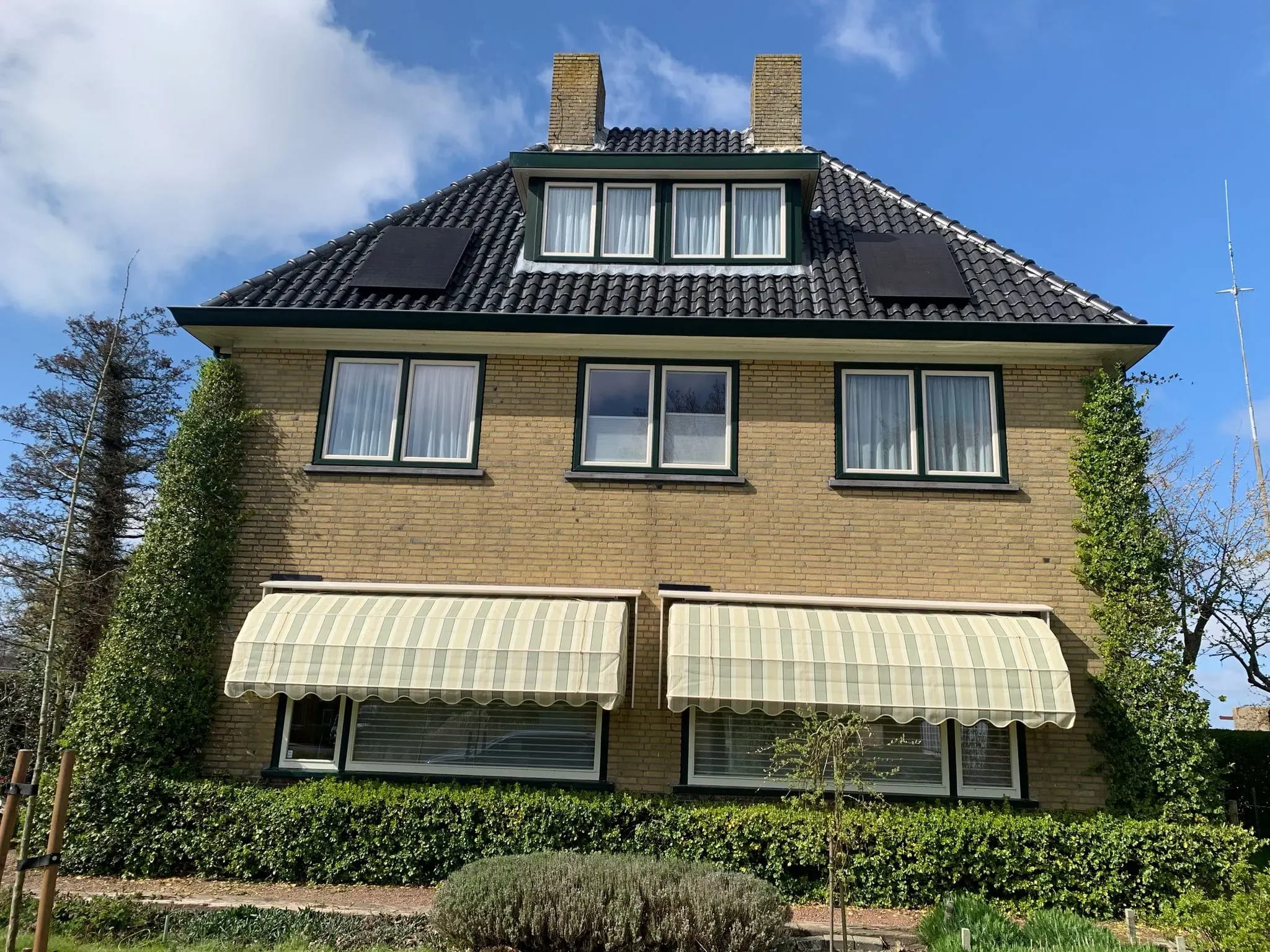 Vrijstaande woning met markiezen boven de benedenramen.