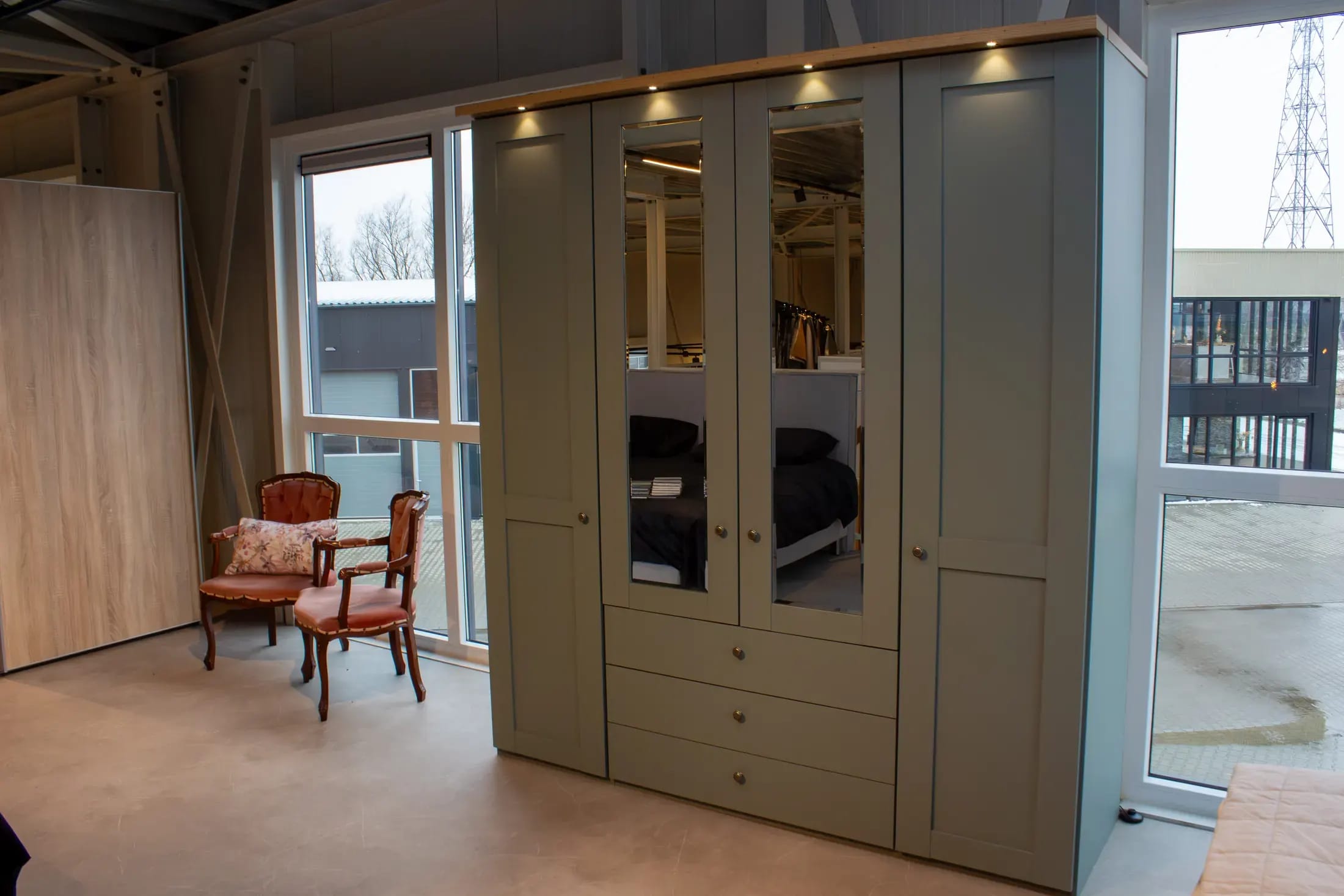 Groene linnenkast met spiegeldeuren, lades en verlichting in de showroom.
