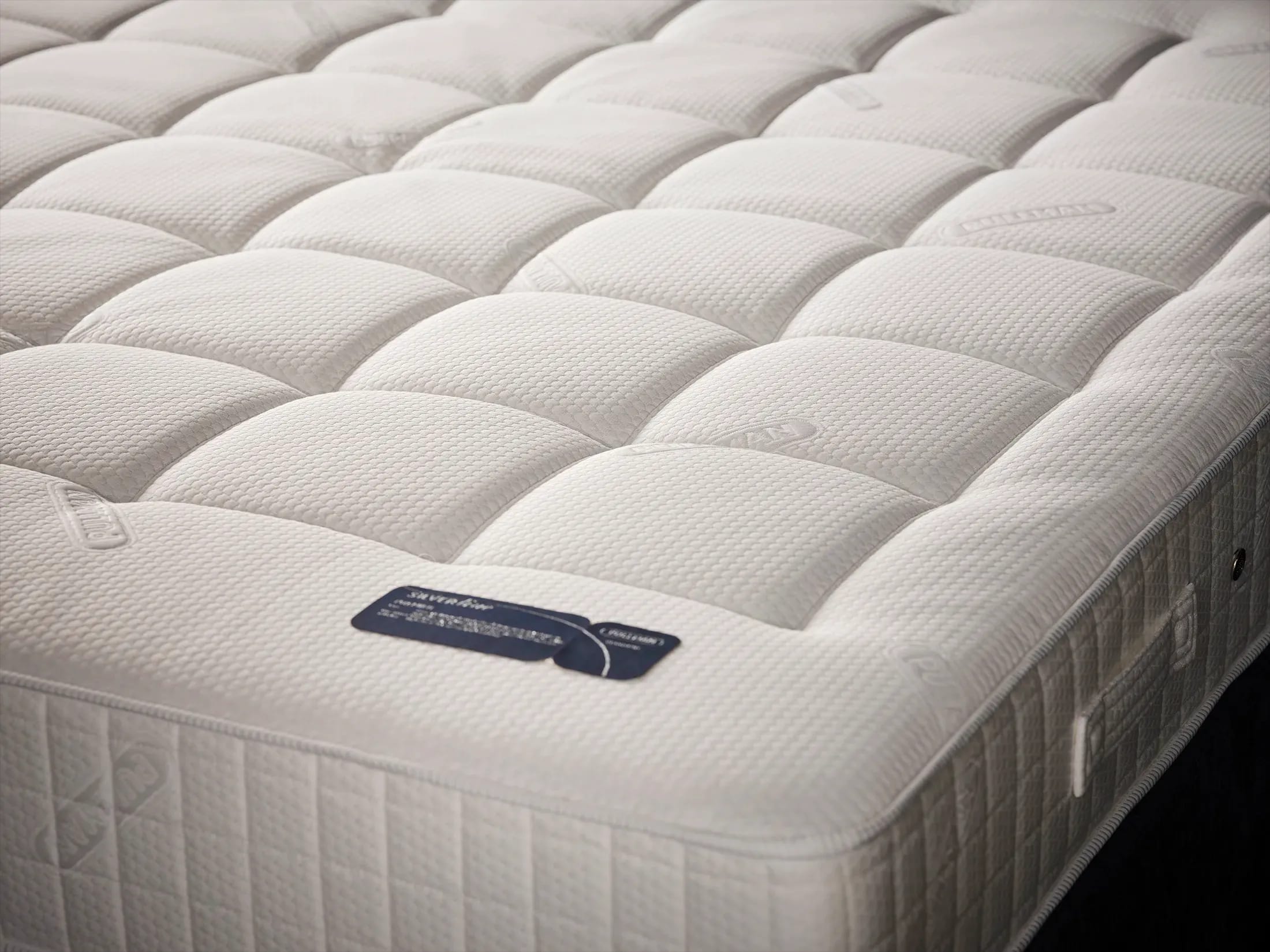 Close-up van een matras met gewatteerde tijk en een zijhandgreep.