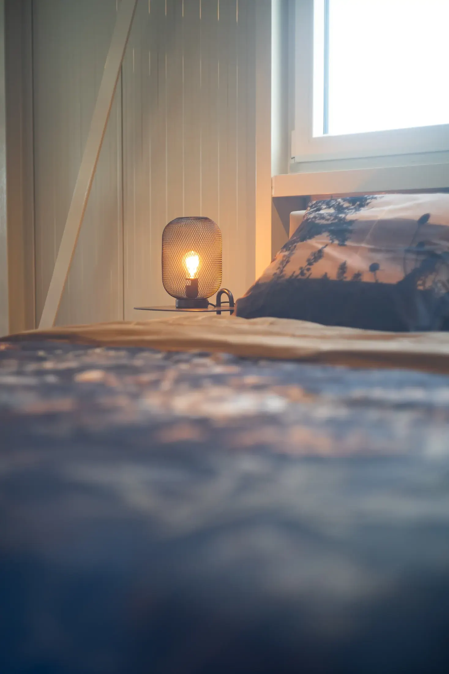 Opgemaakt bed met een sfeerlamp in de slaapafdeling.