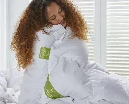 Vrouw knuffelt een wit dekbed.