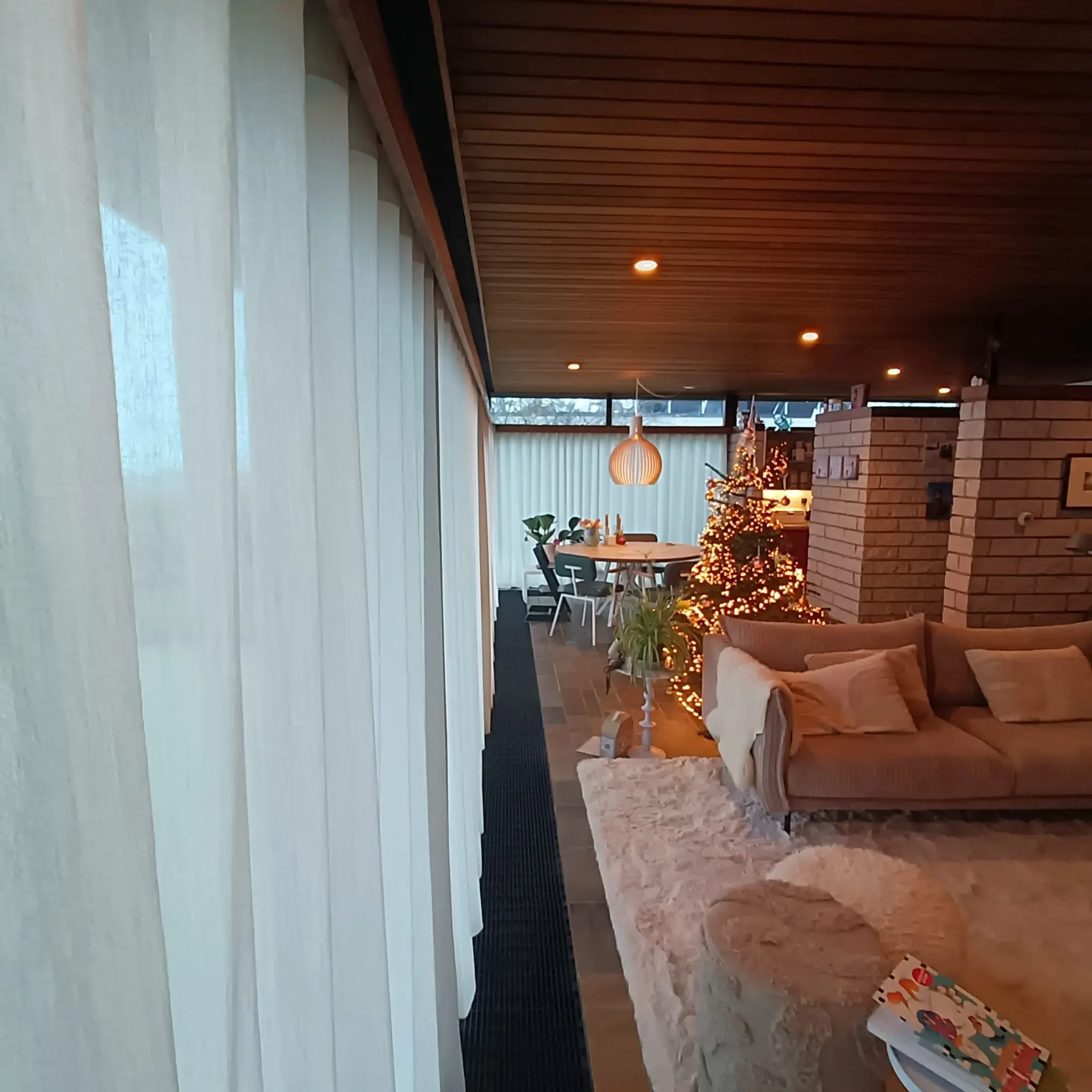 Inbetweens langs de ramen van een woonkamer, met zicht op de zithoek.