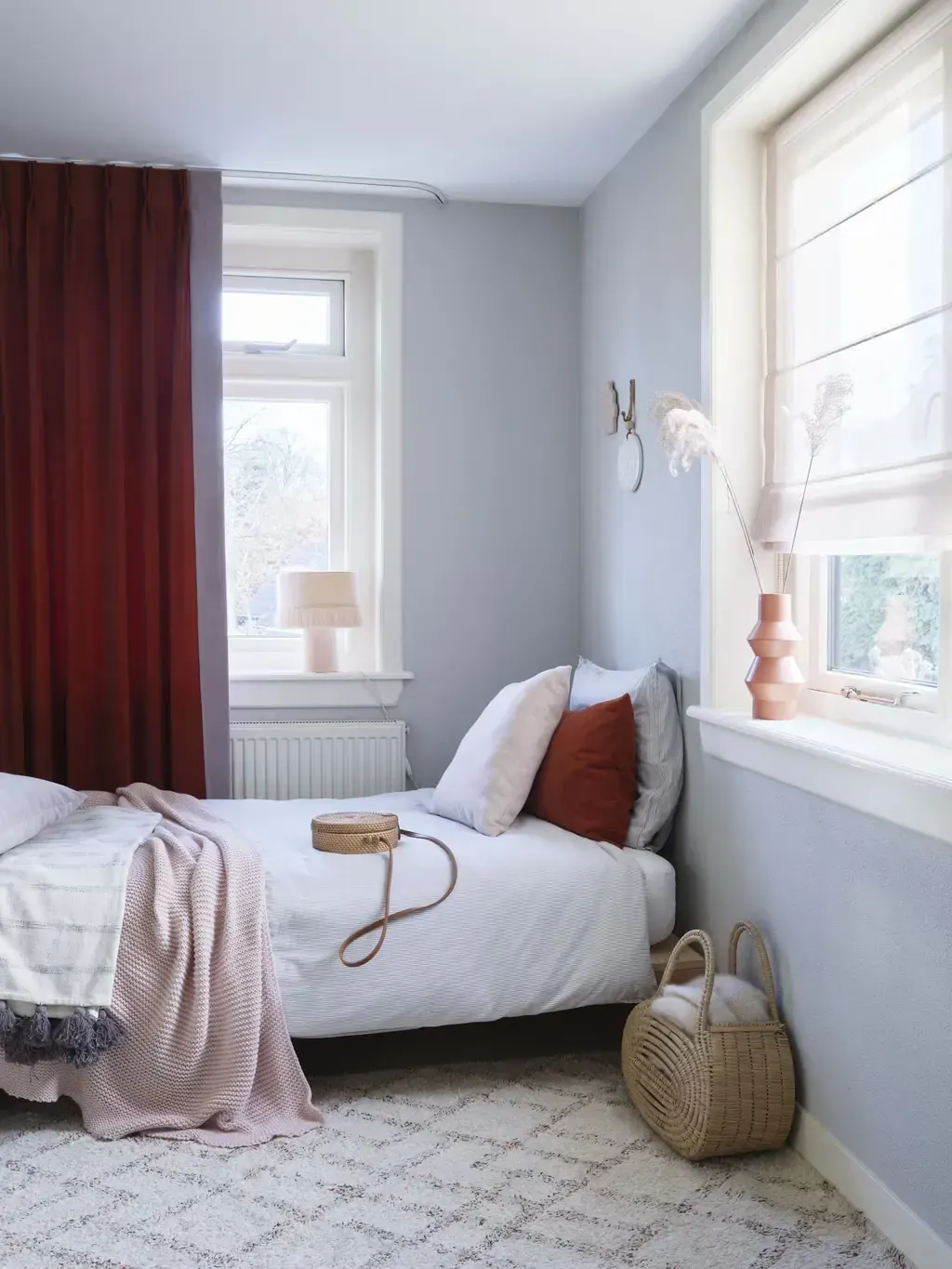 Rode overgordijnen in een lichte slaapkamer.