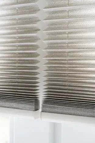 Detail van een zilvergrijs plisségordijn.