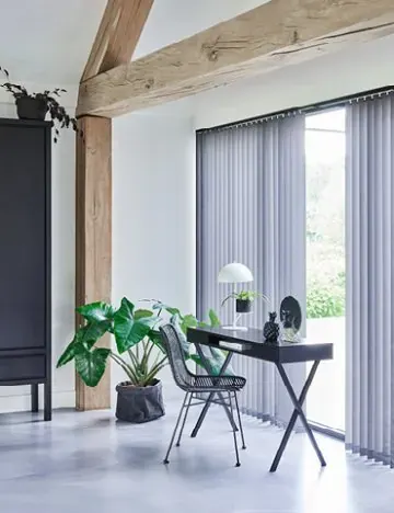 Grijze verticale lamellen voor een schuifpui bij een werkplek.