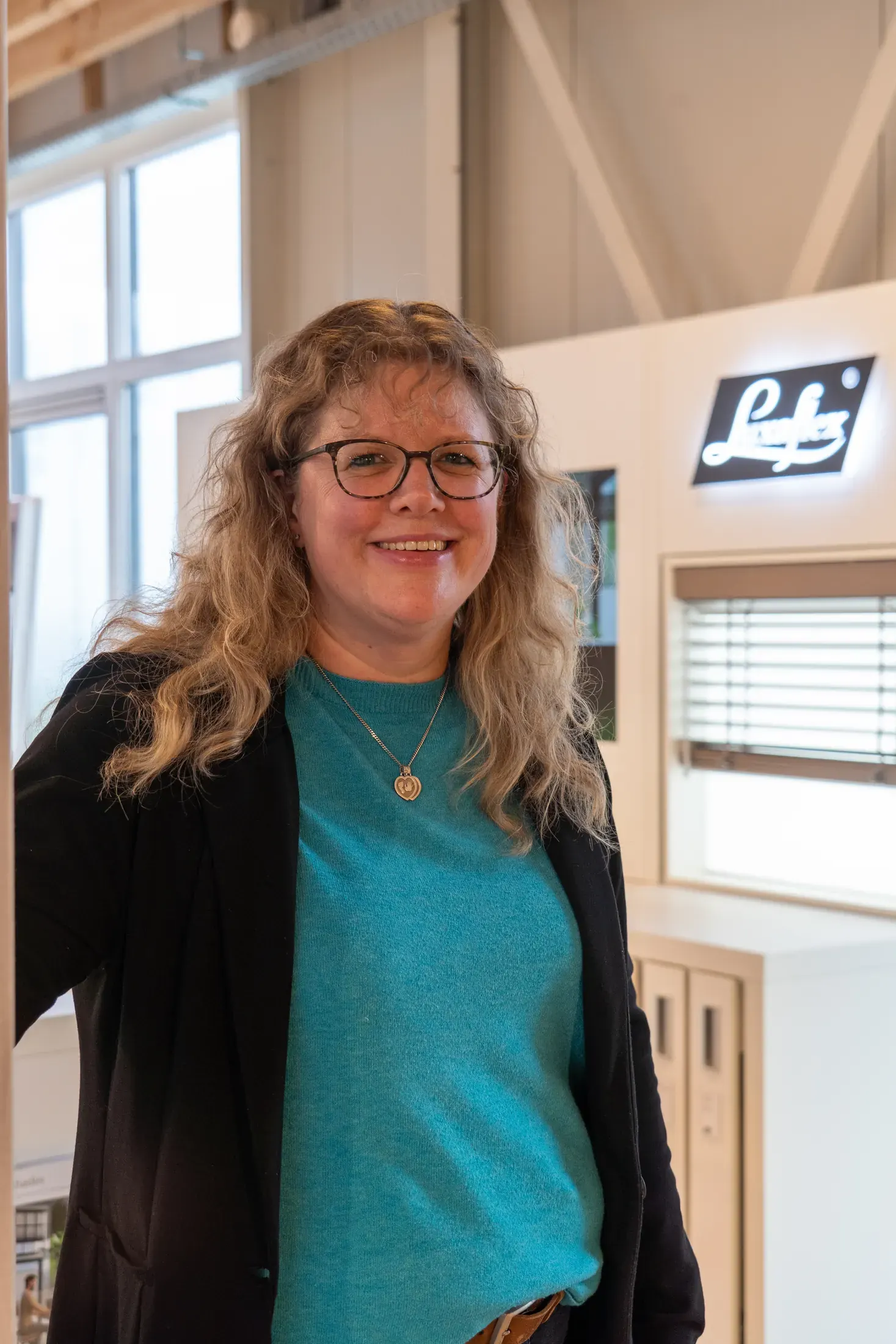 Portret van een lachende adviseuse in de showroom, met de Luxaflex-wand op de achtergrond.